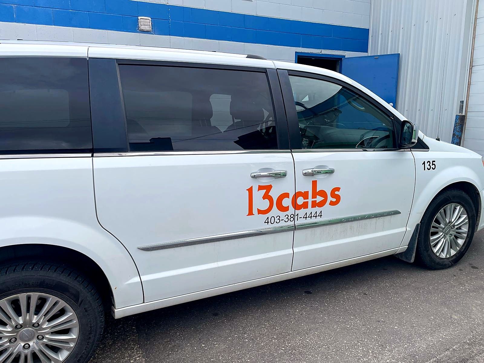 Side view of a white van with 13cabs graphics