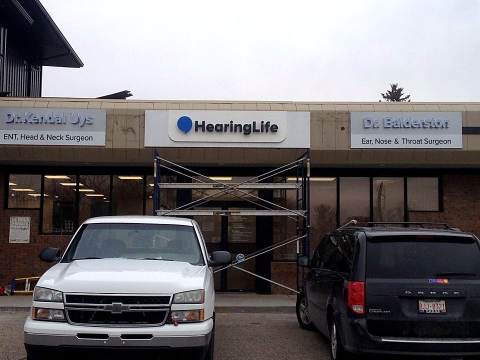 Scaffolding in front of a HearingLife and medical office storefront during sign installation